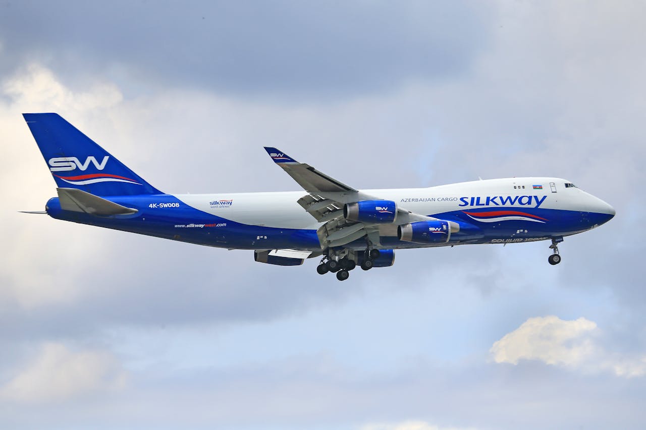 about-img Silk Way cargo aircraft flying amidst a partly cloudy sky, showcasing modern aviation.