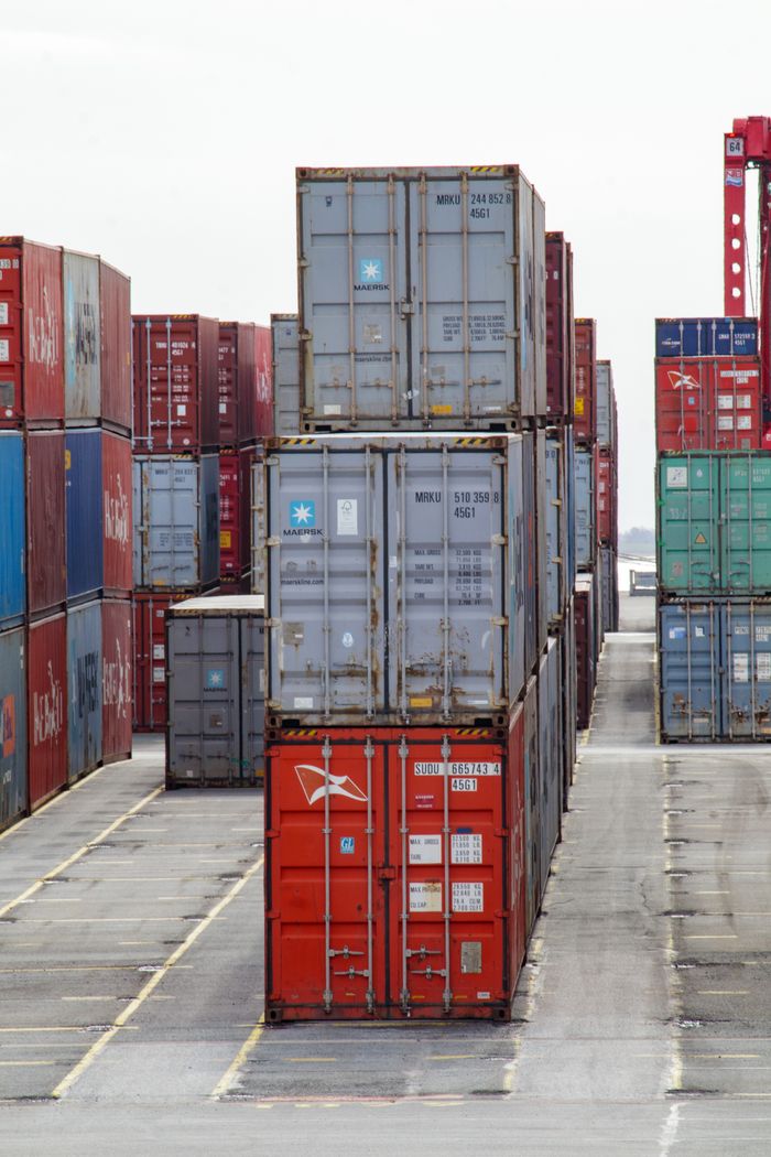 why-choose-us Vertical shot of colorful shipping containers stacked at an industrial port, showcasing logistics.