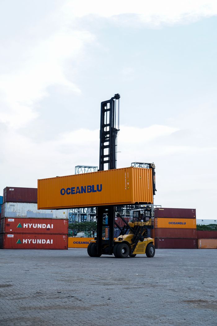 gallery-4 Forklift handling container in bustling Jakarta port with clear skies.