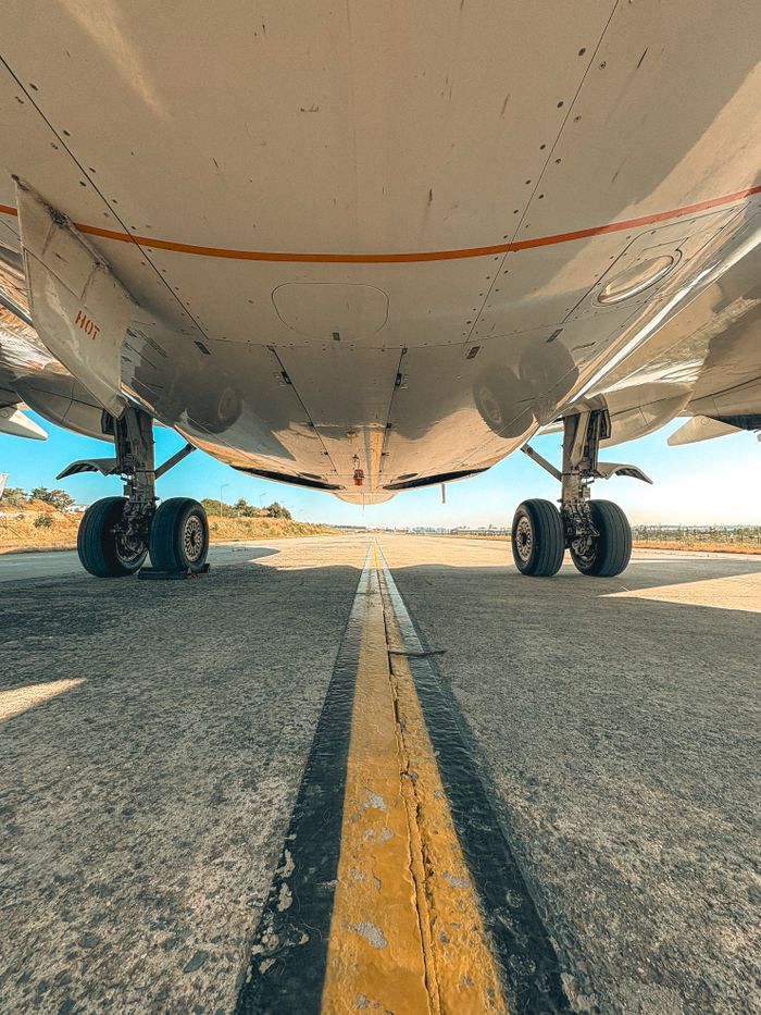 our-experience Detailed view of airplane wheels and undercarriage on a runway during a clear day.
