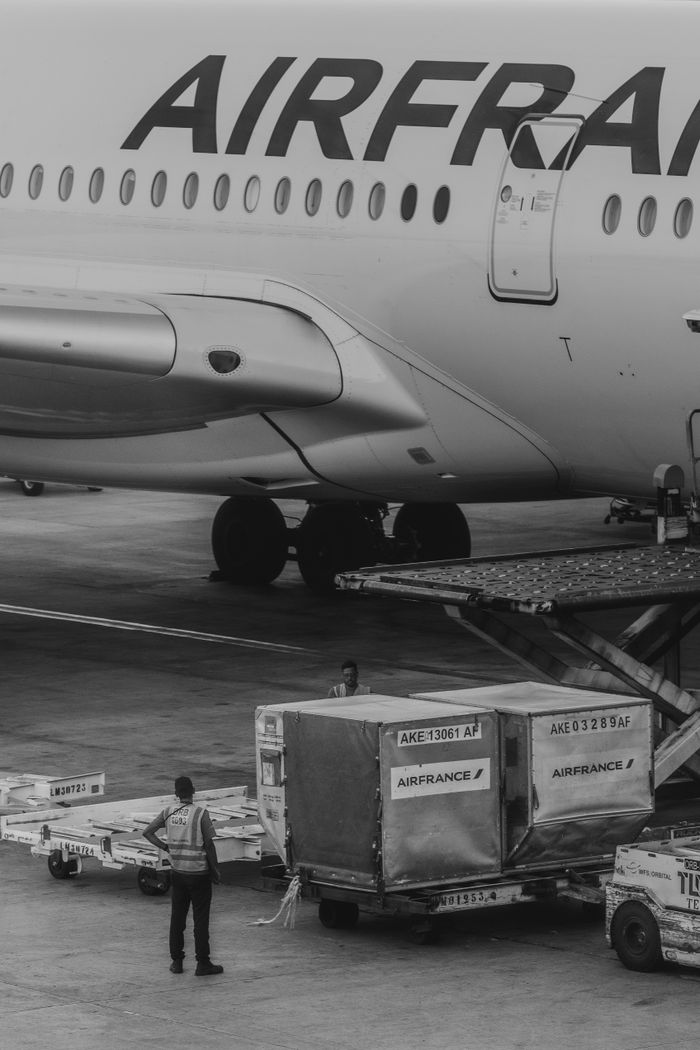 about-02 Monochrome image of Air France airplane cargo operations with worker overseeing loading.