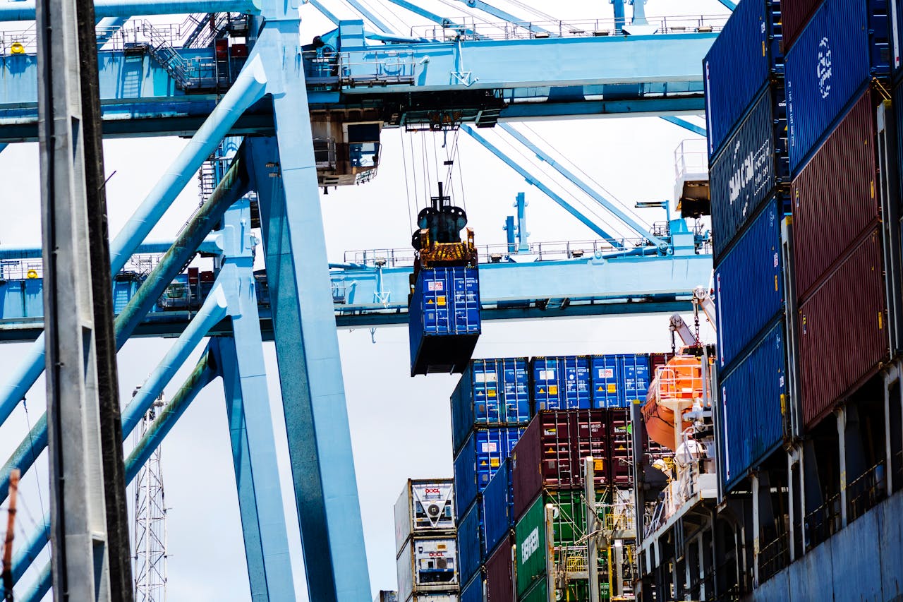 gallery-5 Cargo cranes lifting shipping containers at a bustling industrial port.